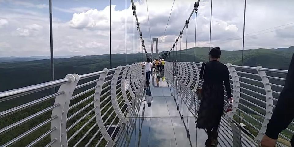 China. Turista fica pendurado a 100 metros de altura após queda de ponte de vidro